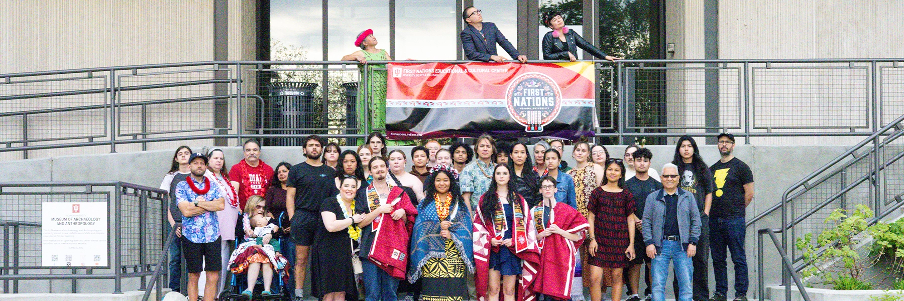 A group photo of FNECC graduating students and their families standing on concrete stairs.